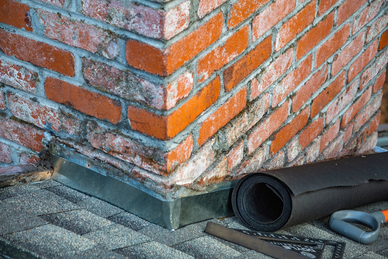 Brick chimney with new flashing and roofing materials