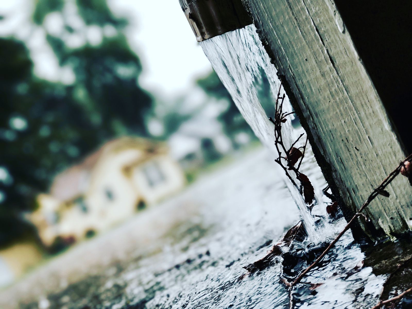 Rainwater pouring off a house roof during a storm