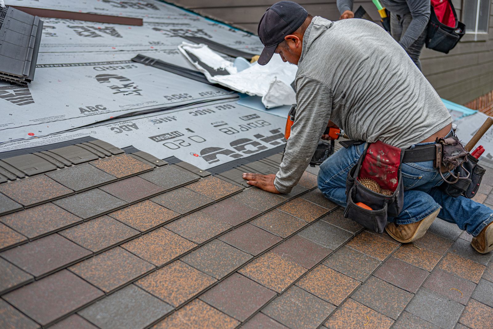 Roofer installing shingles and underlayment