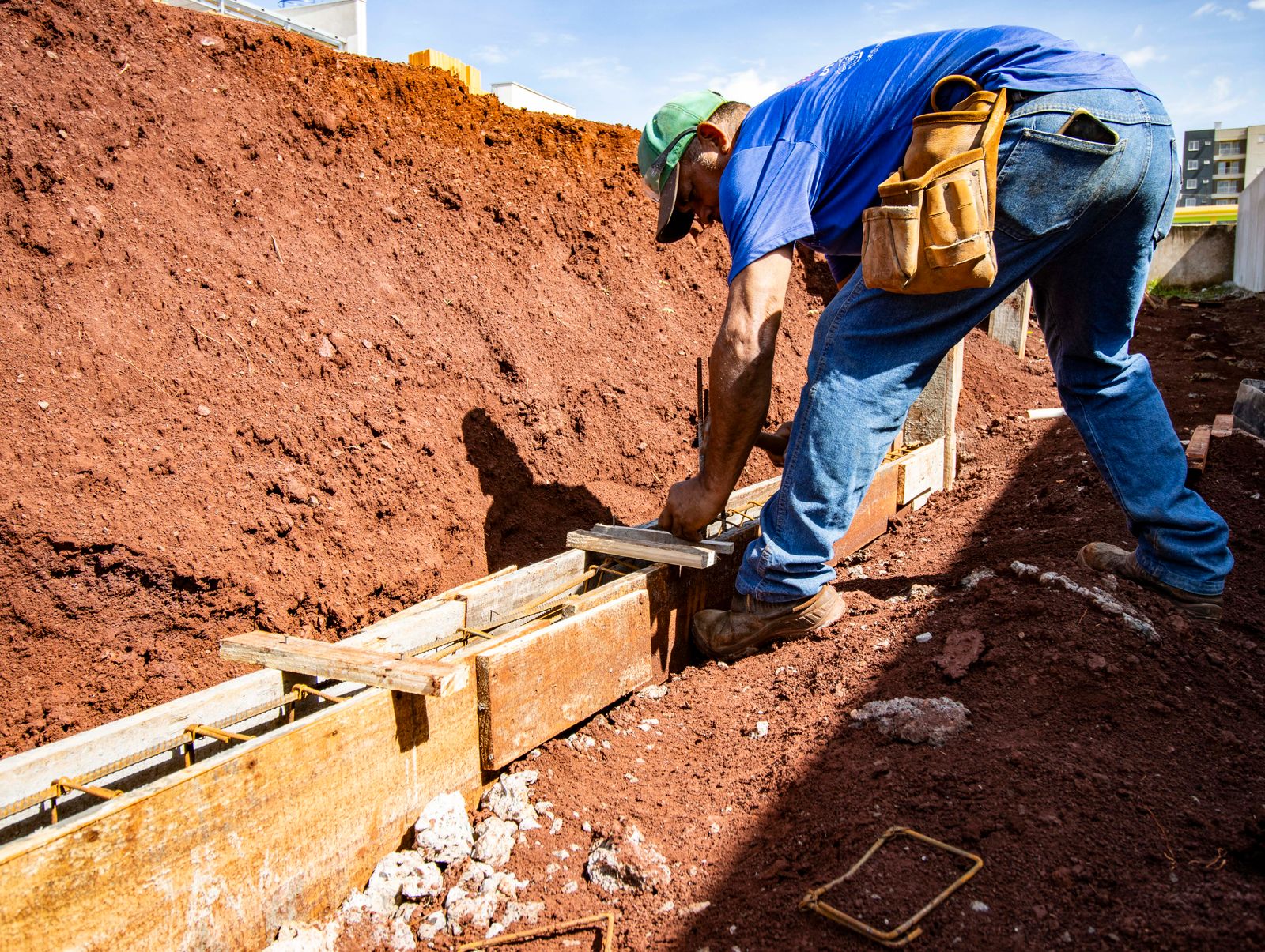 Worker building a foundation footing form in an open excavation